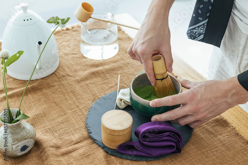 Traditional Japanese green tea match close-up. Matcha tea ceremony, a bamboo Chassen whisk for whipping and tea in a bowl on the brown background.