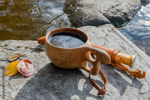 Coffee from handmade wooden coffee cup on a hike by the lake in autumn