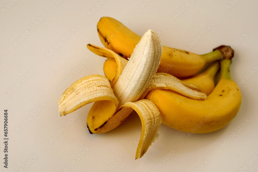 Close-up of a half-peeled ripe banana in a person's hand,