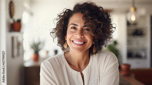 A portrait of a beautiful Hispanic looking woman wearing white shirt in her house, office, housewife, working from home, lifestyle blog