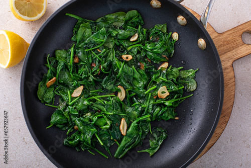 Canvas-taulu Sauteed garlic spinach in a pan with slices of crispy garlic