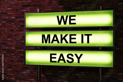 We make it easy. Black letters on a green illumintaed light box, red brick wall. Easy going, positive emotion, never mind, relaxation, motto, slogan, cool attitude, effortless. 3D illustration