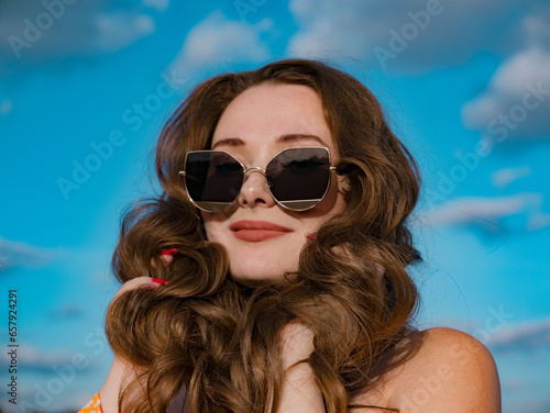 young brunette in sunglasses against the sky close-up © Ruslan