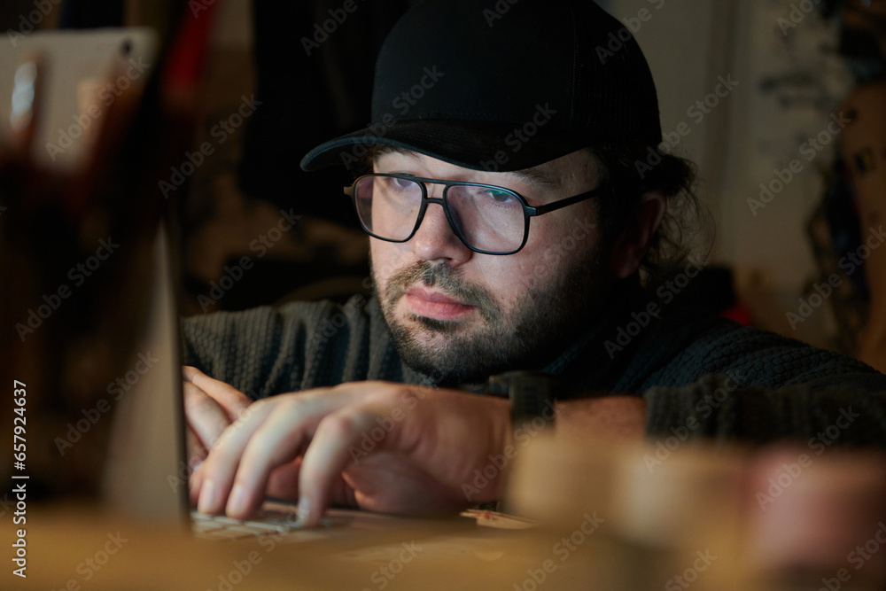 A close-up shot of a man using a laptop in a dimly lit room, engrossed in his digital work during the late hours of the night A close-up shot of a man using a laptop in a dimly lit room, engrossed in his digital work during the late hours of the night