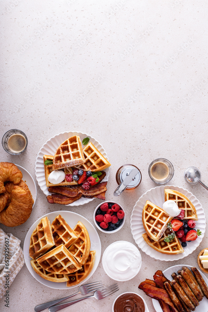 Breakfast table with waffles, bacon, breakfast sausage, croissants and berries Breakfast table with waffles, bacon, breakfast sausage, croissants and berries