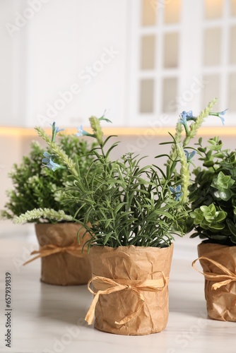 Artificial potted herbs on white marble table in kitchen. Home decor