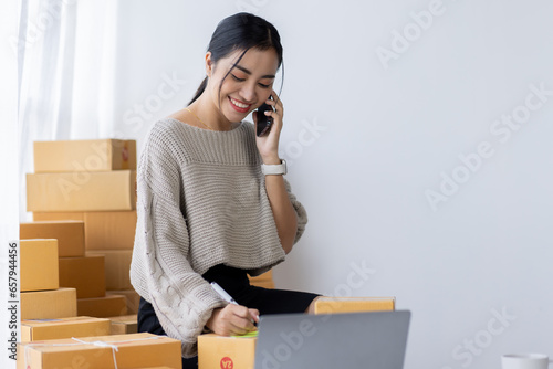 Starting small businesses SME owners asian female entrepreneurs call phone on receipt box and check online orders to prepare to pack the boxes, sell to customers, SME business ideas online.