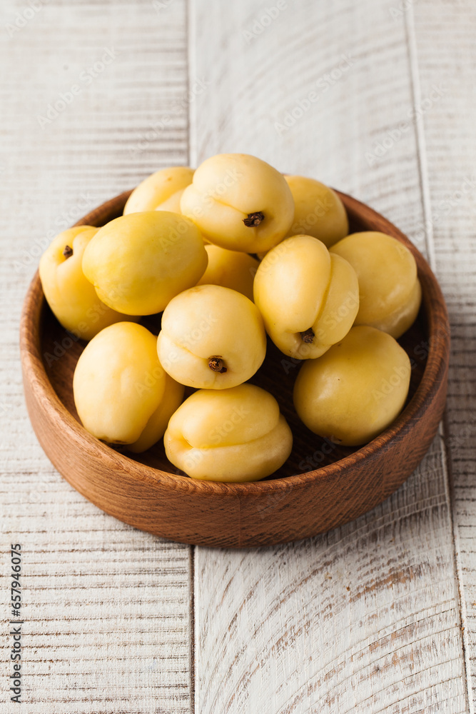 Ripe juicy sweet apricots in a wooden plate on a light wooden background. Fruit and harvest 