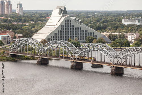 Panorama of the Daugava river in Riga, latvia, with a train from Latvian railways over dzelzcela tilts or Riga Railway Bridge with a skyline of business skyscrapers in background with high rise towers photo