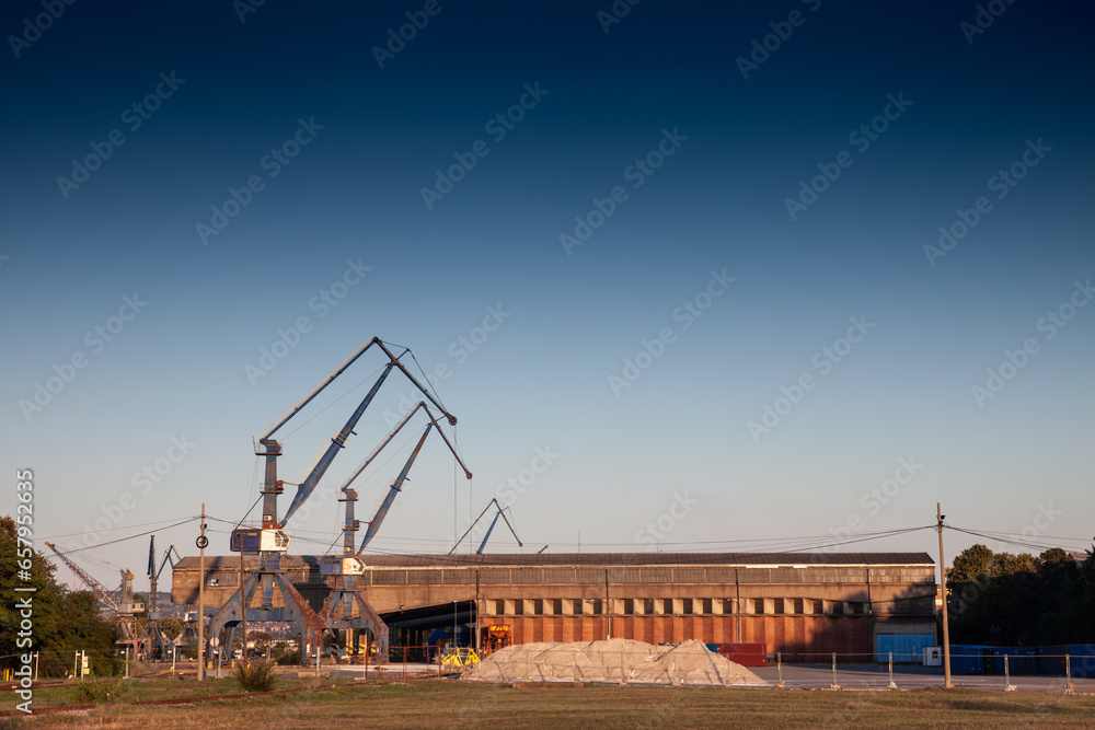 Selective blur on a panorama of Port cranes and warehouses on a river and sea port terminal of Balkans on Belgrade Port, used to load, unload containers & other cargo in Import and export operations.