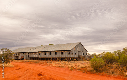 A sheep shearing shed with red dirt and an overcast sky as background in Currawinya National Park in Queensland, Australia. photo