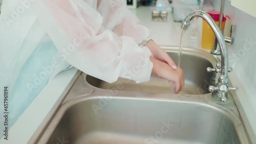 Woman doctor dentist washes her hands in metal sink before work in dentistry. photo
