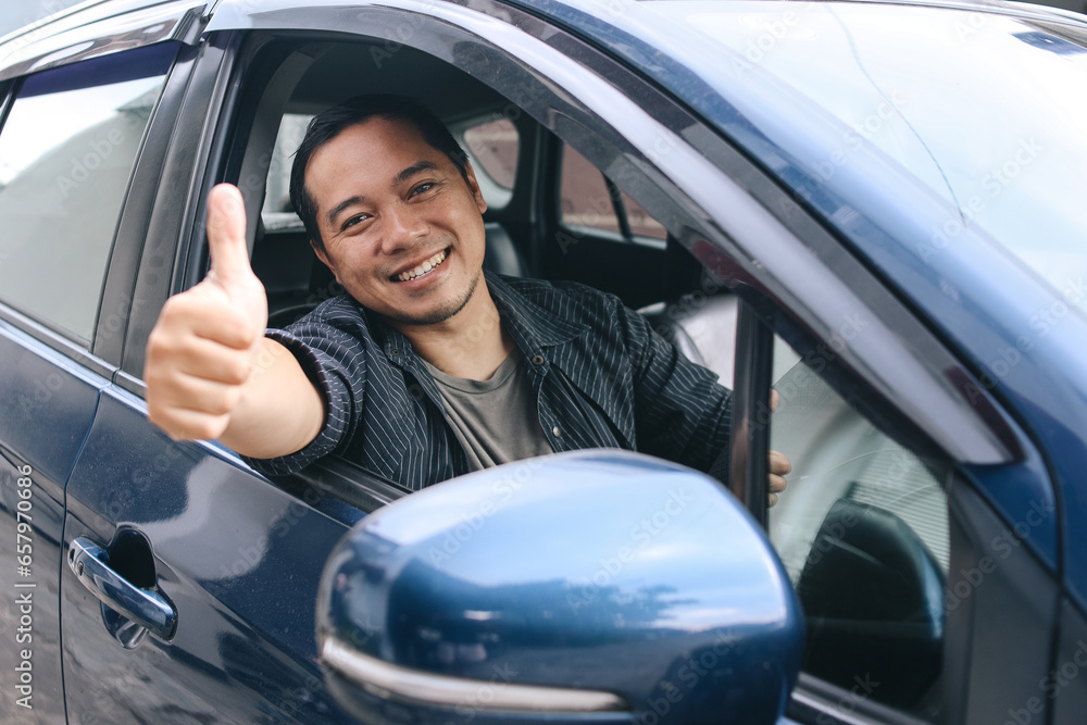 Asian driver man smiling and showing thumb up on his car