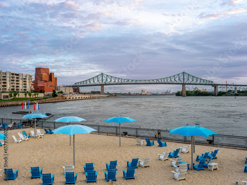 Plage de la tour de l'horloge du vieux-port de Montréal au lever du soleil. La plage est déserte, seul, les goélands l'occupent. On voit le pont Jacques-Cartier au loin.