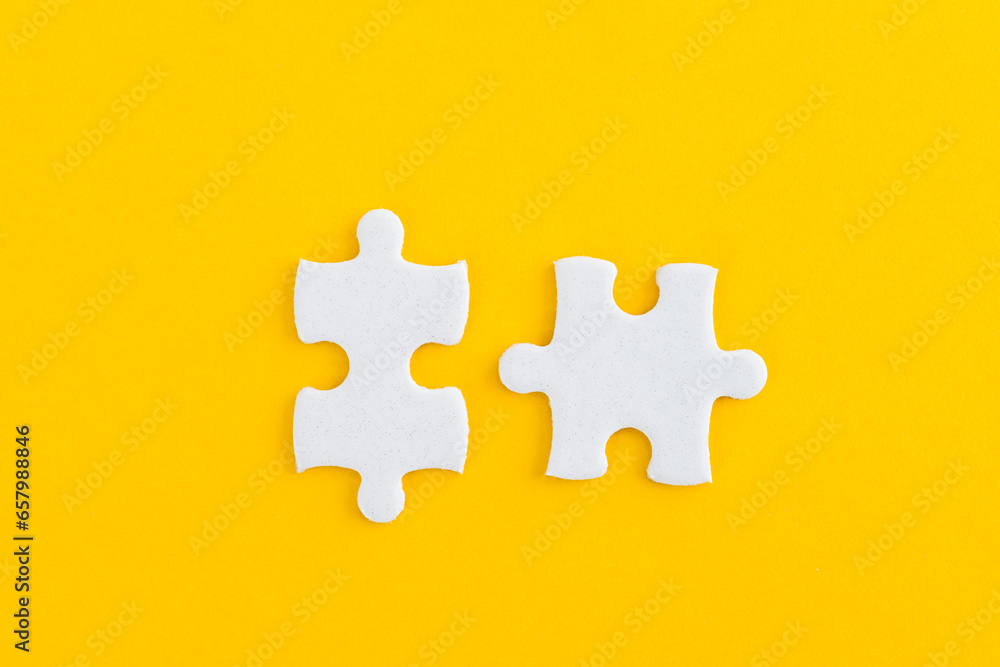 Obraz premium Two puzzle pieces on yellow background