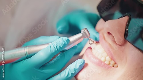 Stomatologirst makes hygienic cleaning teeth in dentistry for woman.