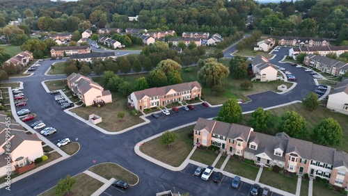 American neighborhood of apartment complexes in suburbs. Aerial reveal of many houses, homes, and duplexes next to rural fields. photo