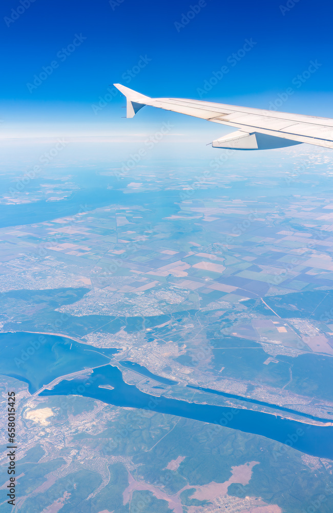 Aerial view from airplane window above green ground. View from the airplane window with beautiful clouds at sunrise Aerial view from airplane window above green ground. View from the airplane window with beautiful clouds at sunrise