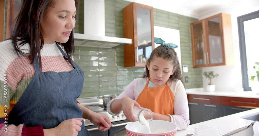 Happy biracial mother and daughter preparing dough and smiling in sunny kitchen Happy biracial mother and daughter preparing dough and smiling in sunny kitchen