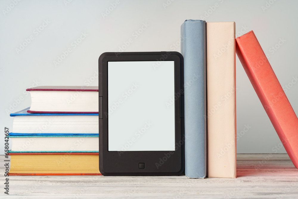 Digital tablet with a stack of books on gray background Digital tablet with a stack of books on gray background