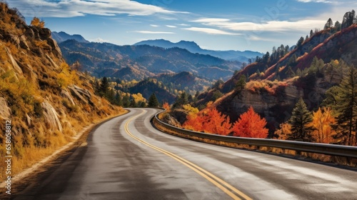 Autumn mountain road. The scene unfolds against a backdrop of tree-covered peaks, their leaves creating an unforgettable contrast against the deep blue sky.