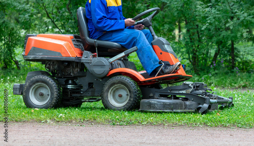 A lawnmower mows the grass in the park