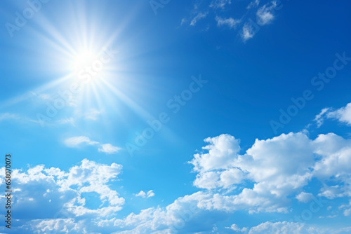 Clear blue sky with white soft clouds and a shining sun in the background of a beautiful cloudscape.