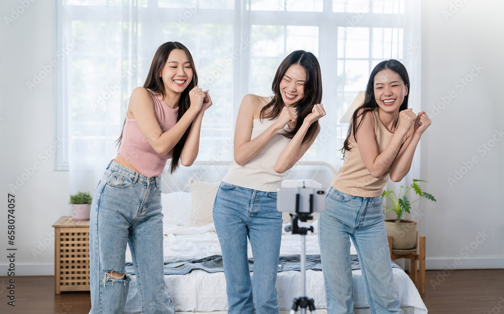 Young asian female influencer girl group record video on smartphone, dancing on camera at bed room home. Positive lifestyle vlog make content for blog, filming for social mediaAsian young woman