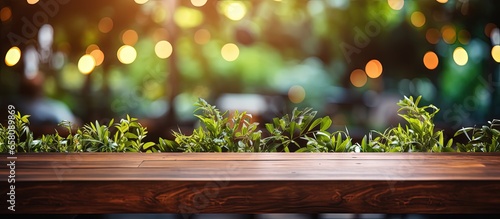 Table made of wood with bokeh light effect and outdoor garden featuring green leaves in the blurry background