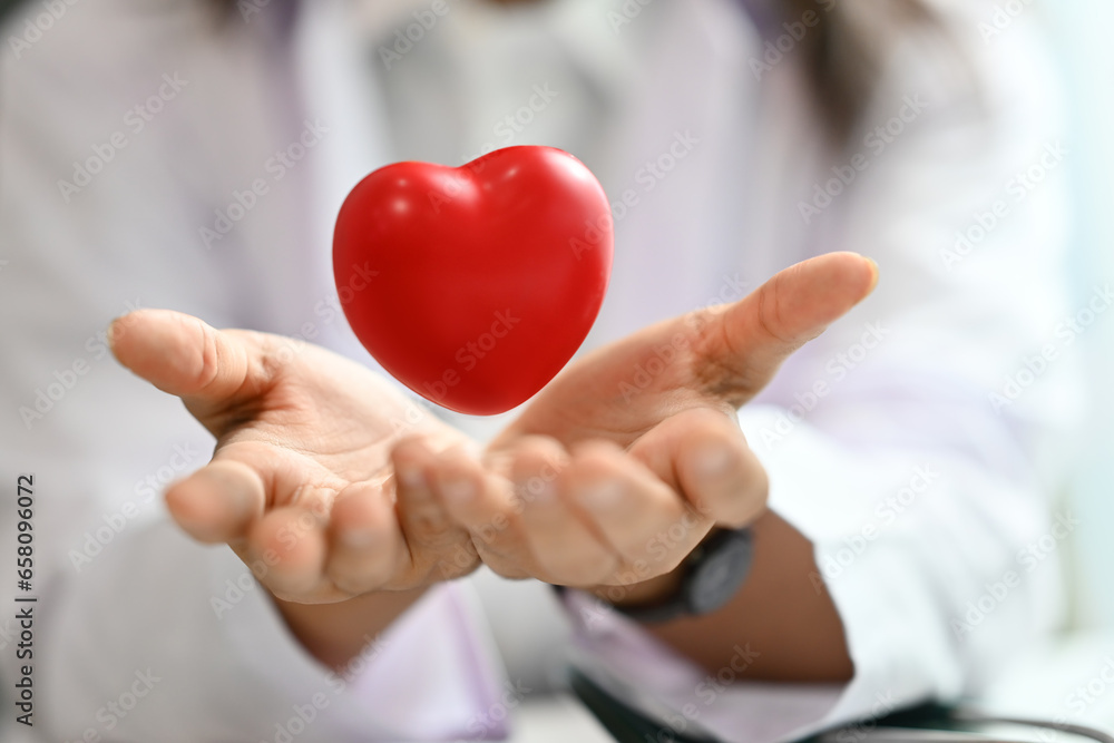 Red heart floating over opened hands. Health care, cardiological, medical and charity concept Red heart floating over opened hands. Health care, cardiological, medical and charity concept