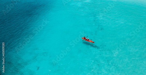 Aerial view of kayak with people in blue turquoise sea. Kayaking, leisure activities on the ocean. Active travel, outdoor exotic destination recreational water sport. Tropical ocean bay amazing scene
