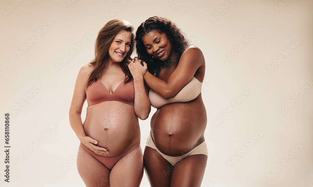 Friends with bellies: Two women holding hands and supporting each other through pregnancy - obrazy, fototapety, plakaty 