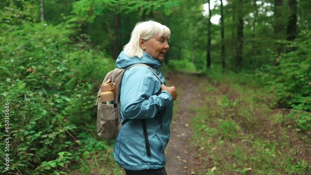 Portrait of active 50s senior woman with tourist backpack walking alone through summer forest wild nature enjoying hiking adventure alone. Portraits. High quality FullHD footage Portrait of active 50s senior woman with tourist backpack walking alone through summer forest wild nature enjoying hiking adventure alone. Portraits. High quality FullHD footage