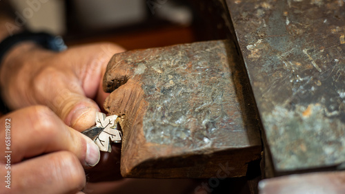Foto Goldsmith working and creating in his crafting gold jewelry workshop with a burin