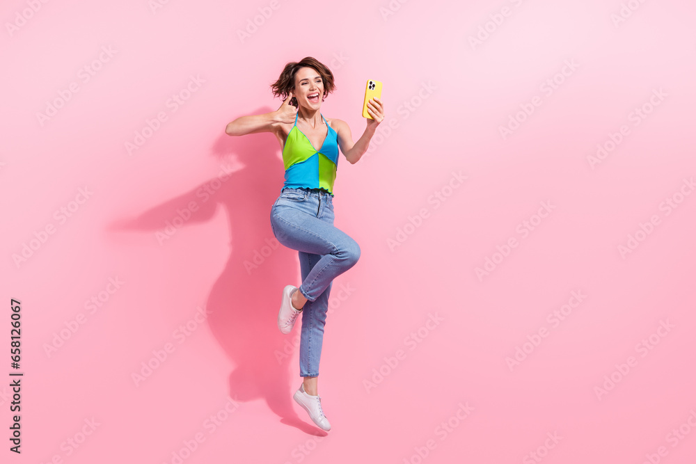 Full body photo of jumping girl recording video using front camera her smartphone thumb up like sign isolated on pink color background Full body photo of jumping girl recording video using front camera her smartphone thumb up like sign isolated on pink color background