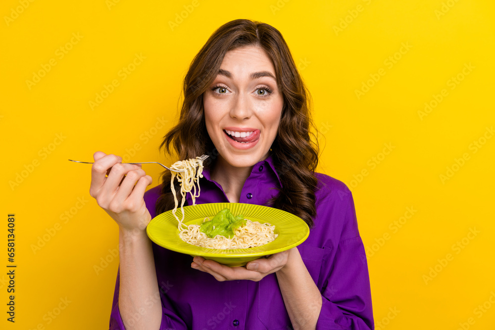Portrait of excited cheerful person tongue lick teeth hands hold fork spaghetti plate isolated on yellow color background - obrazy, fototapety, plakaty 