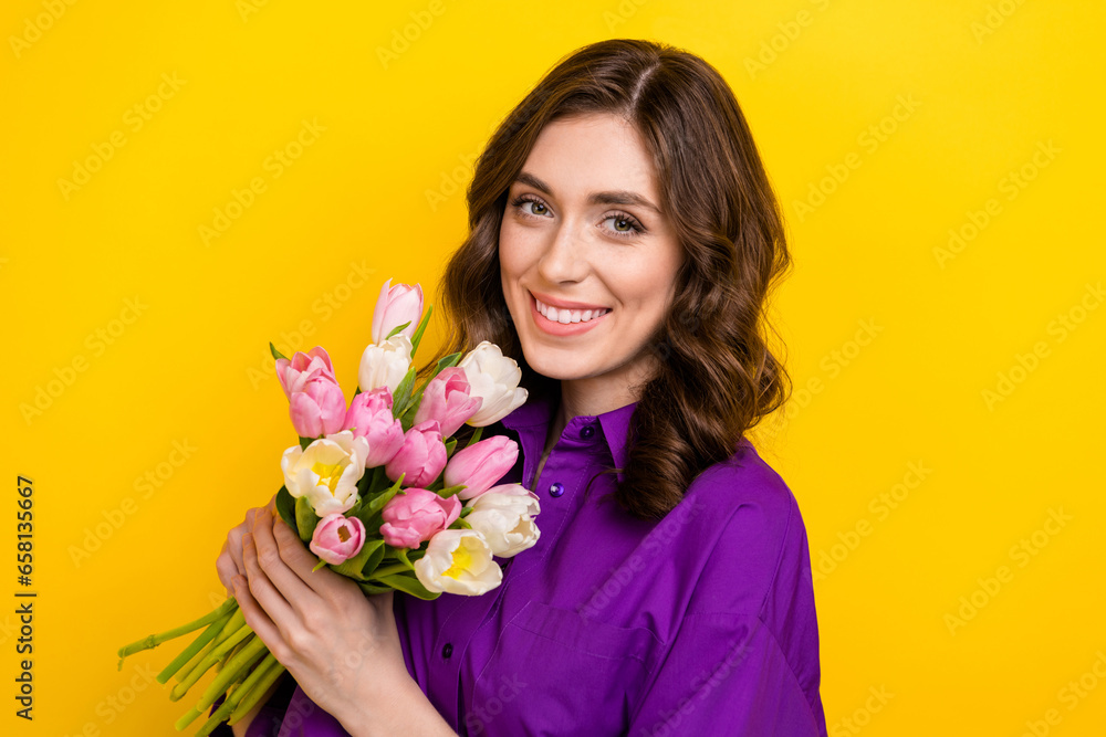 Photo of stunning cheerful person toothy smile hands hold fresh tulip flowers isolated on yellow color background Photo of stunning cheerful person toothy smile hands hold fresh tulip flowers isolated on yellow color background