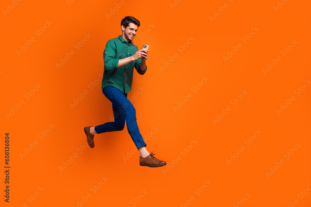 Full body photo of funky young business guy success businessman running with smartphone fast specialist isolated on orange color background