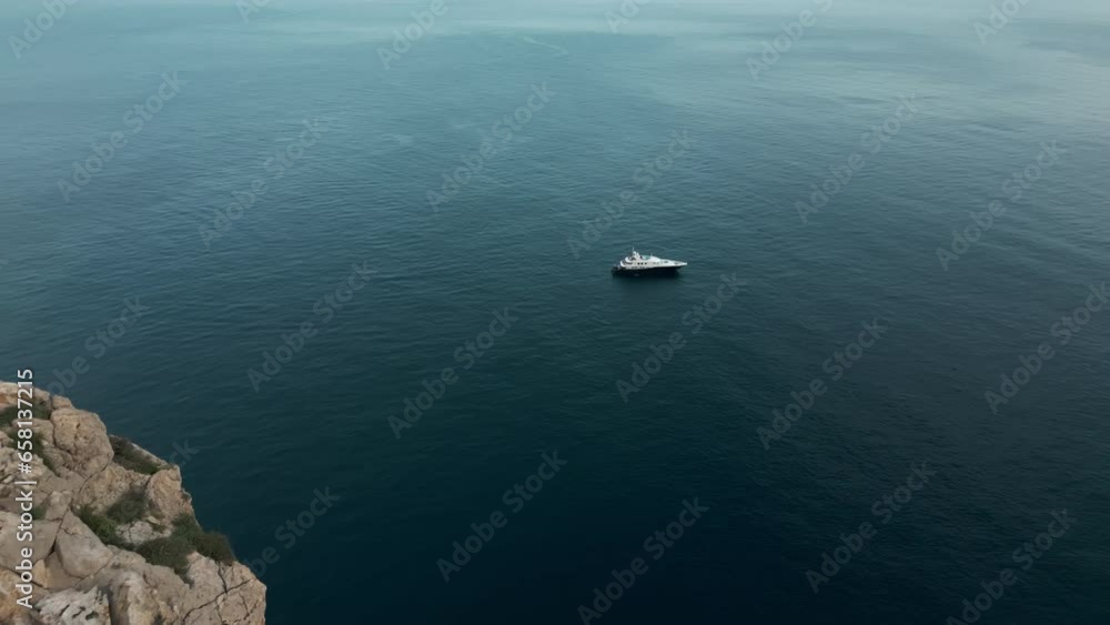 Aerial view of Floating yacht against Es Verda rocks. A big yacht floating alone in the blue sea Aerial view of Floating yacht against Es Verda rocks. A big yacht floating alone in the blue sea