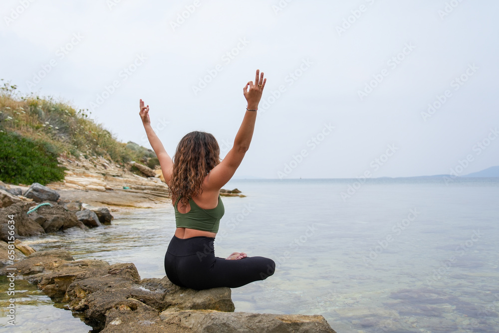 Woman practicing yoga by the sea on the rocks Woman practicing yoga by the sea on the rocks