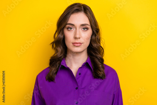 Photo of good mood serious candid sincere woman with wavy hairstyle dressed purple shirt look at camera isolated on yellow background