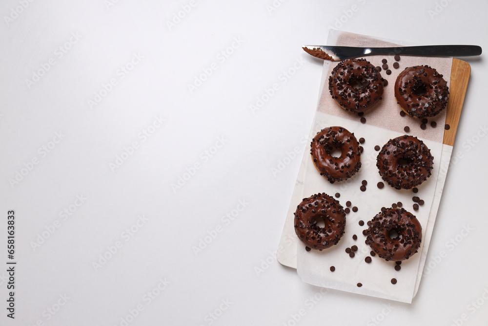 Chocolate donuts on kitchen board on white background, space for text Chocolate donuts on kitchen board on white background, space for text
