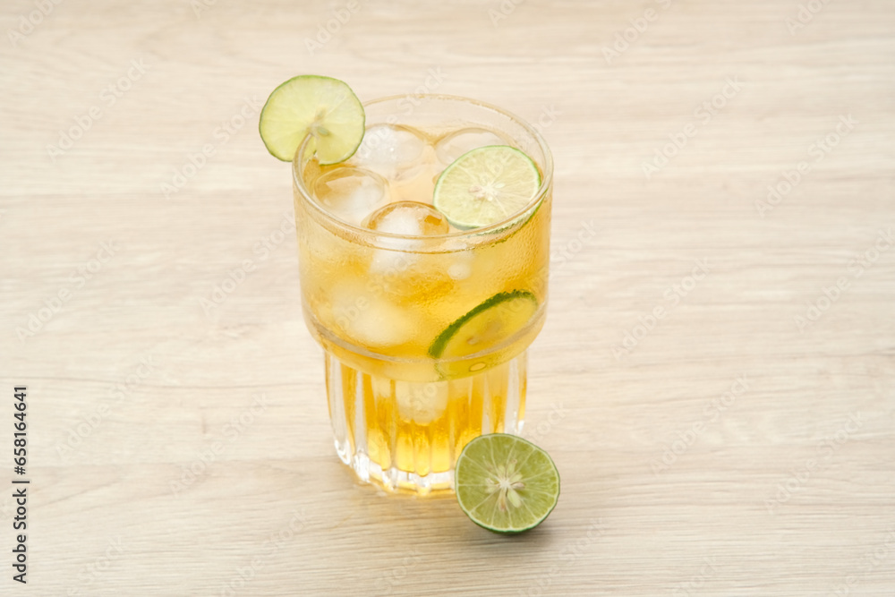 Fototapeta premium Iced tea with lime on a wooden table, refreshing drink 
