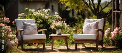Wooden armchairs placed outdoors on a wooden floor for summer relaxation Garden scene with chairs in nature vase of flowers and backyard surroundings Holiday theme