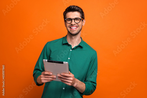 Photo of cool positive guy wear green shirt communicating modern gadget isolated orange color background