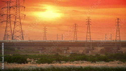 At dusk and sunset, a high-speed train passes over the bridge. Sugarcane grass along the Zengwen River at dusk. Tainan City. photo