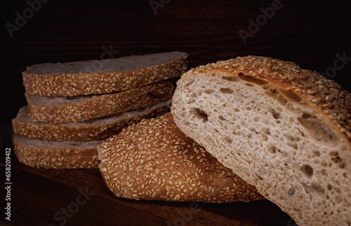 Cut loaf of bread and pieces of bread on a wooden background. Ciabatta bread.