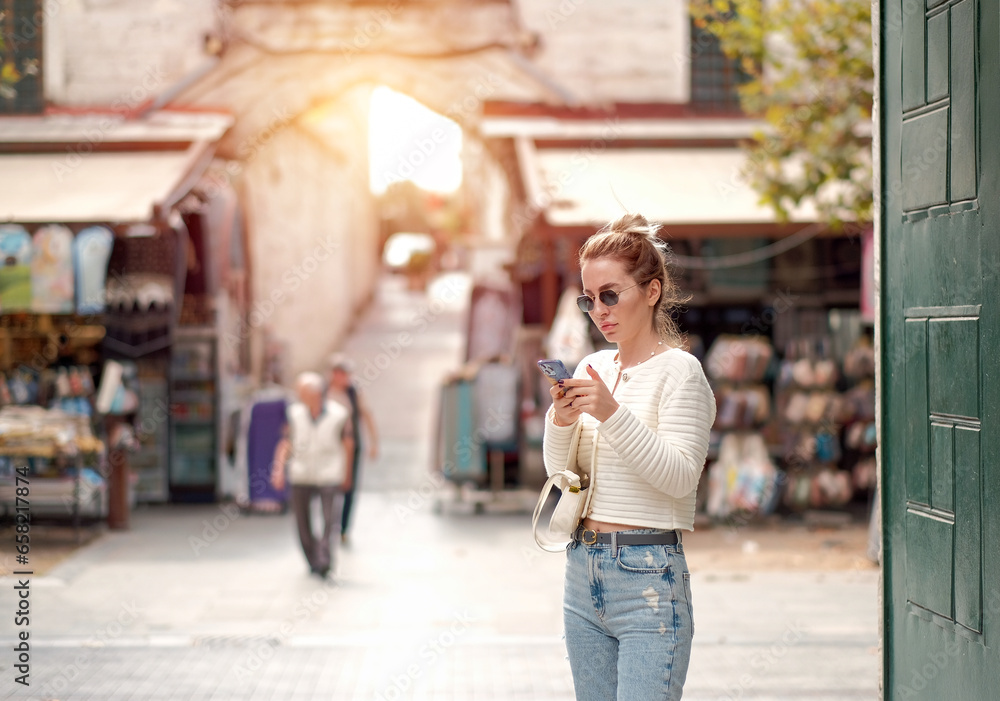 Young Attractive Blonde Lady in a White Ukrainian Shirt and Blue Classic Base Jeans While Chatting on the Phone. Happy Sexy Woman On The Street. Phone addiction. Young Attractive Blonde Lady in a White Ukrainian Shirt and Blue Classic Base Jeans While Chatting on the Phone. Happy Sexy Woman On The Street. Phone addiction.