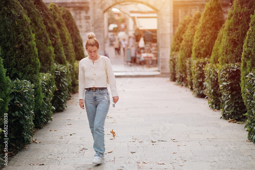 A young Attractive Blonde Lady in a White Ukrainian Shirt and Blue Classic Base Jeans While Walking in The Park. Happy Sexy Woman On The Street.