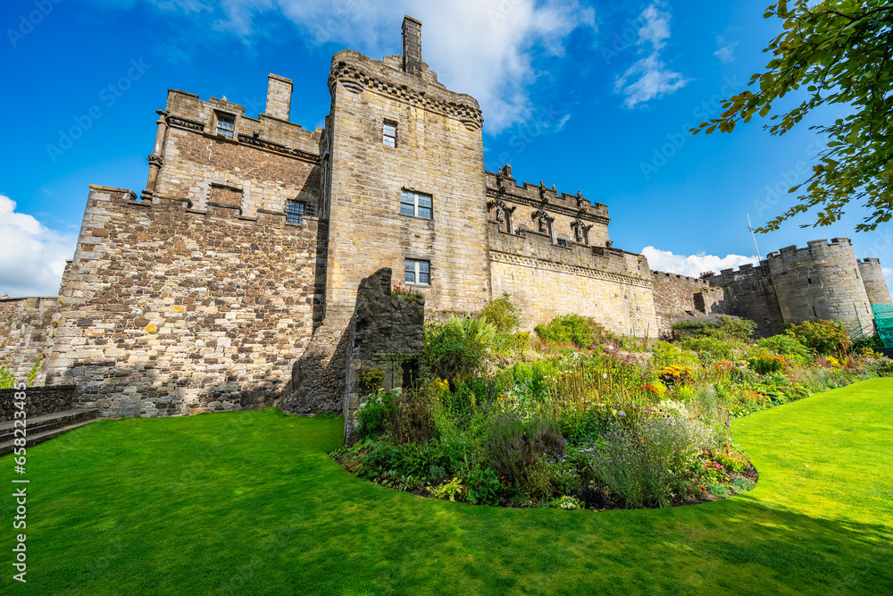 Main facade of medieval Stirling Castle with flower-filled gardens at the foot of the walls, Scotland.